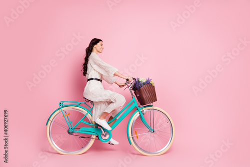 Fototapeta Naklejka Na Ścianę i Meble -  Full length body size photo woman riding bile with flowers dotted dress looking copyspace smiling isolated pastel pink color background