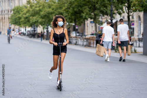 Young woman riding a scooter in the city during coronavirus outbreak © SYCprod