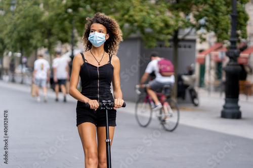 Young woman riding a scooter in the city during coronavirus outbreak