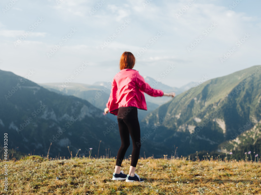 A traveler in leggings, sneakers and a jacket are resting in the mountains in nature A traveler in leggings, sneakers and a jacket are resting in the mountains in nature