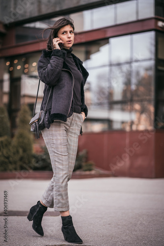 Beautiful young business woman talking on phone in city. Female using mobile phone on the street