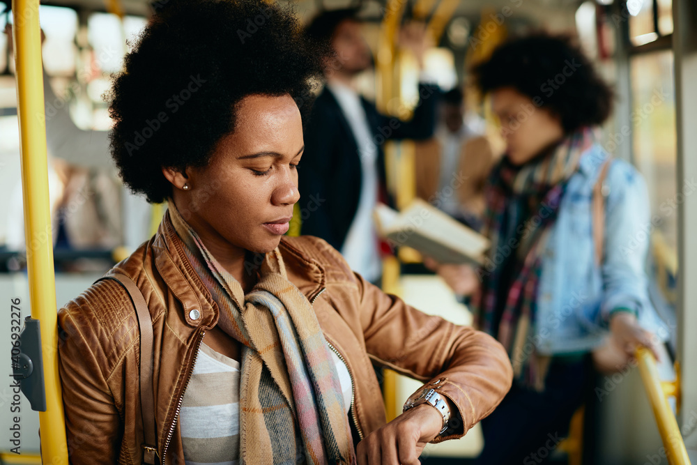 African American woman checking time on wristwatch while commuting by bus. African American woman checking time on wristwatch while commuting by bus.