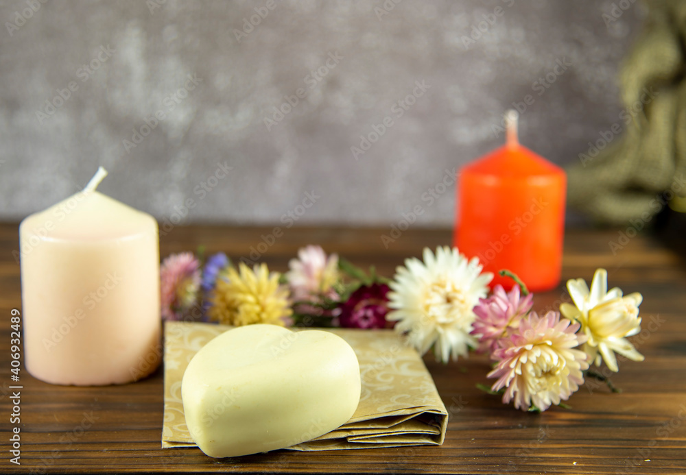 Natural handmade skincare. Handmade natural soap, candles and flowers on the dark wooden countertop.