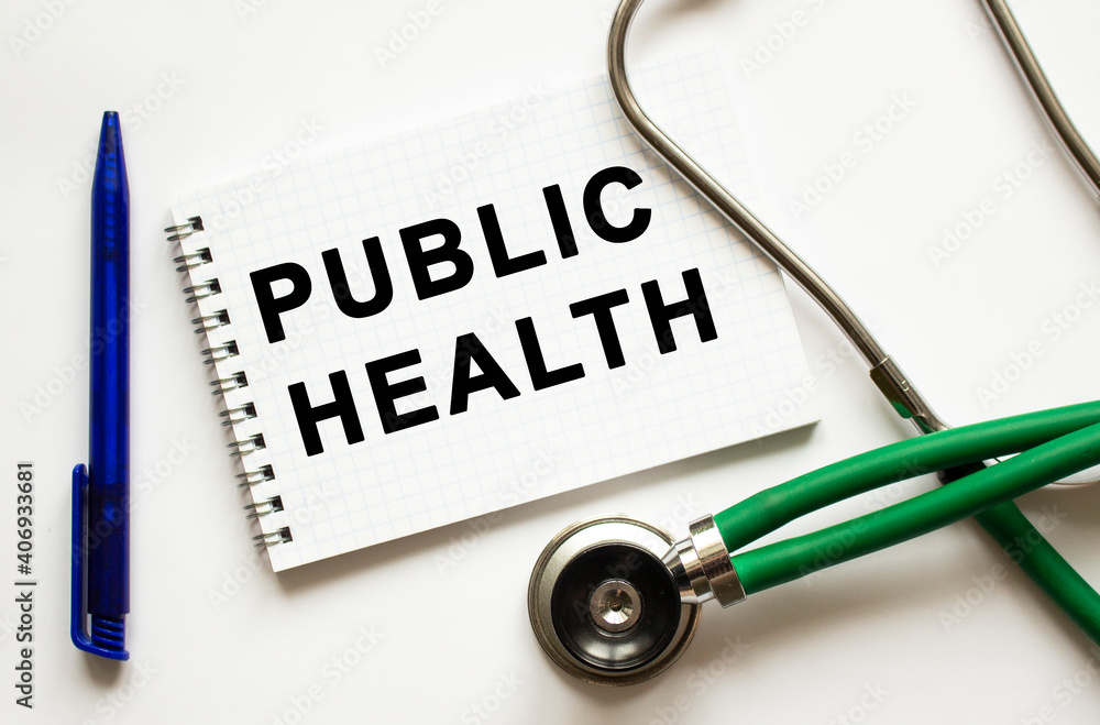 PUBLIC HEALTH is written in a notebook on a white table next to pen and a stethoscope. PUBLIC HEALTH is written in a notebook on a white table next to pen and a stethoscope.