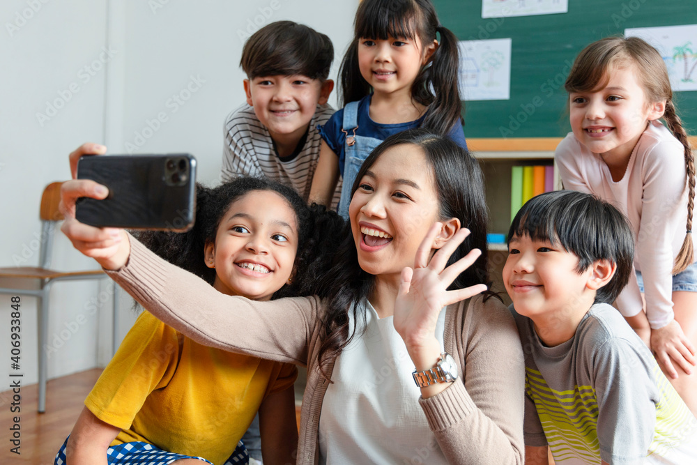 teachers use smartphones to take selfies with a group of students. teachers use smartphones to take selfies with a group of students.