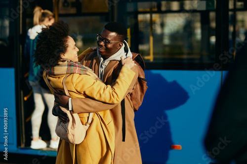 Happy African American couple meeting at bus station.