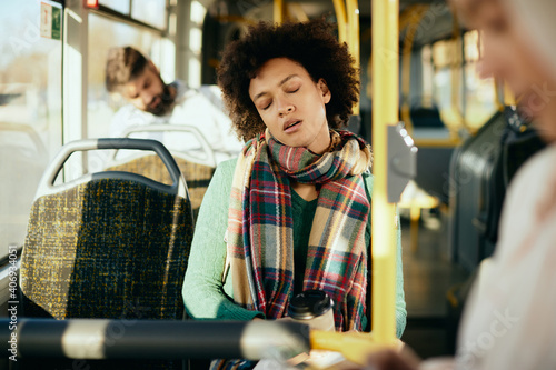 Tired black woman napping while commuting by bus.
