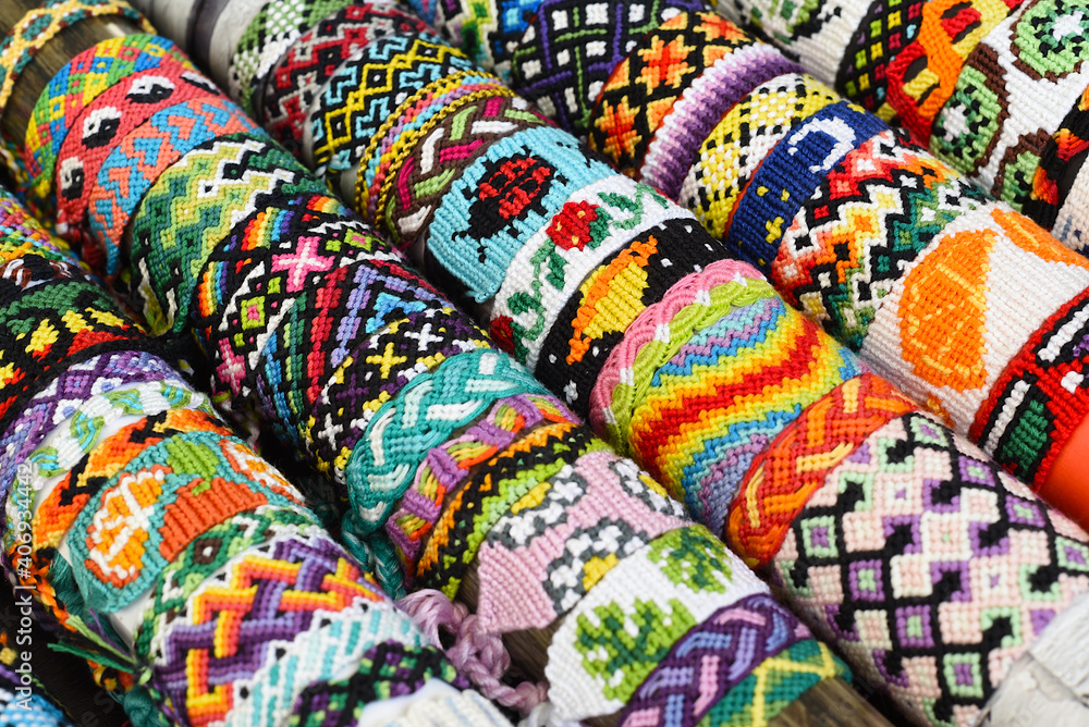 Fototapeta premium Many tied woven DIY friendship bracelets handmade of embroidery floss. Alpha and normal patterns