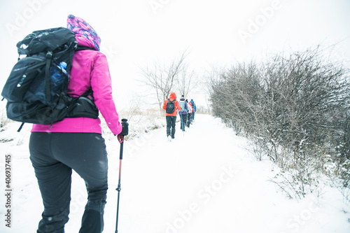 Group of hikers walking on the hike trail on snow winter day.