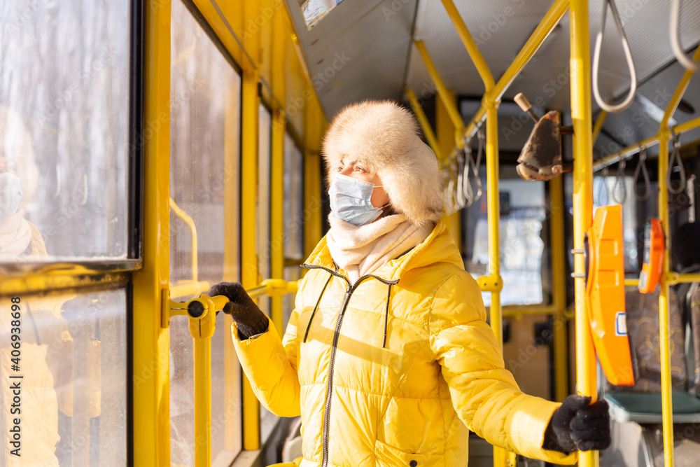 Bright sunny portrait of a young woman in warm clothes in a city bus on a winter day