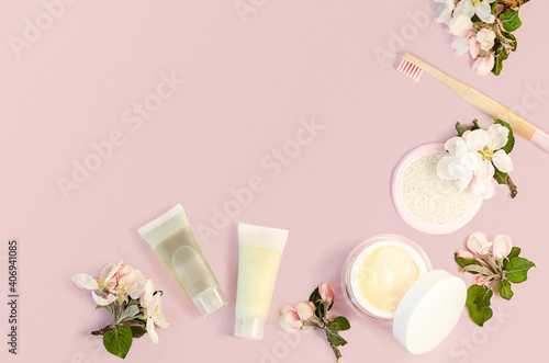 bathroom accessories  product for spring skin care. loofah sponge  cream for face  toothpaste  bamboo toothbrush on pink. natural herbal cosmetics with apple extract  aha acid. text