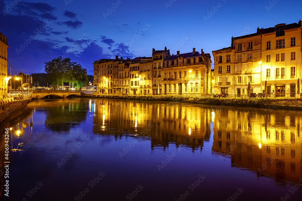 City of Bayonne in France at night with houses of typical architecture and reflections on the Adur River
