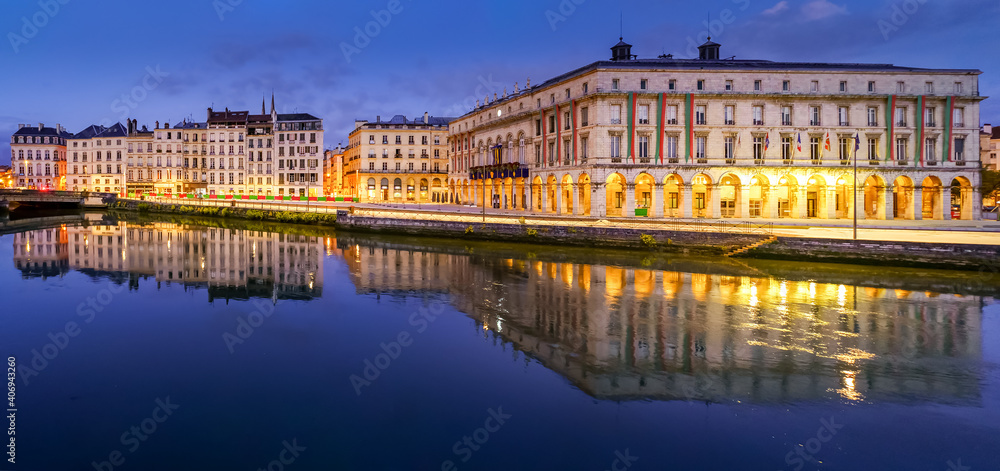 City of Bayonne in France at night with houses of typical architecture and reflections on the Adur River
