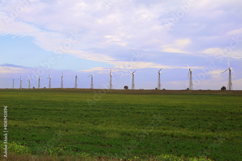windmills, wind turbines stand in a field against a blue sky