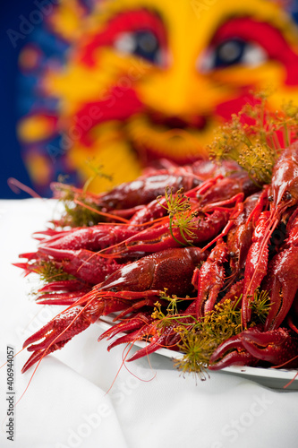 A plate full of cooked crayfish, topped with dill. Swedish tradition. Crayfish party. Studio photo with colorful background. Selective focus on object.