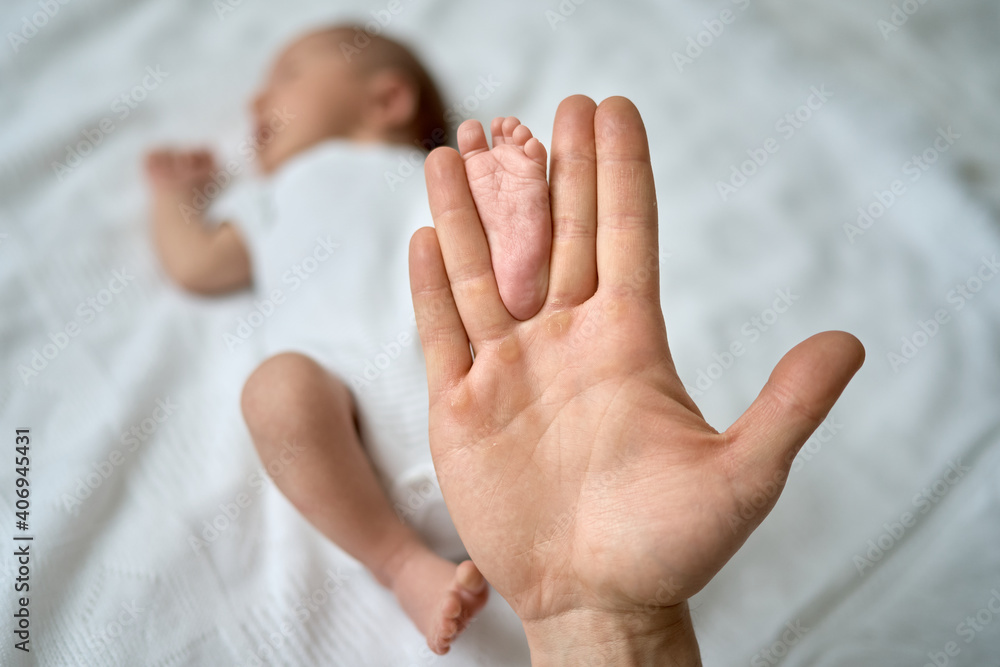 Baby's feet in the father's hands, the foot of a newborn baby, a little baby lies in the crib. . High quality photo Baby's feet in the father's hands, the foot of a newborn baby, a little baby lies in the crib. . High quality photo
