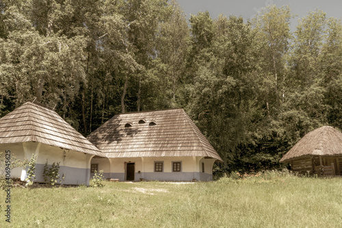 Old, medieval, traditional Ukrainian rural houses on a hill in the forest. Old photo.