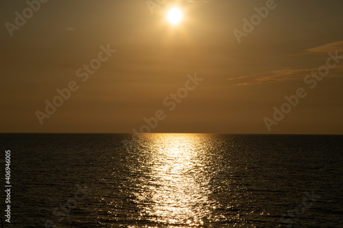 Sunset silvery beige tone. Calm sea with sunset sky and sun through the clouds over. Meditation ocean and sky background. Tranquil seascape. Horizon over the water.