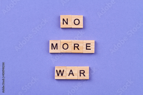 International peace concept. Slogan no more war written with letters on wooden cubes. Isolated on blue background. photo