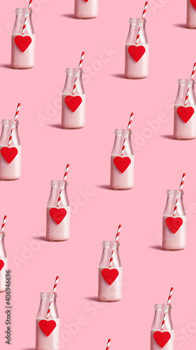 Valentines food pattern made with milk bottles with heart and straws on pastel pink background. Minimal love, drink, or wedding concept.