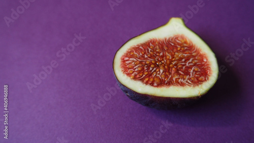 half of a ripe juicy fig with a red center on a lilac background side view . healthy sweet fruits