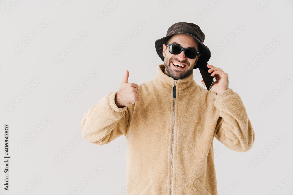 Joyful handsome guy showing thumb up while talking on cellphone Joyful handsome guy showing thumb up while talking on cellphone