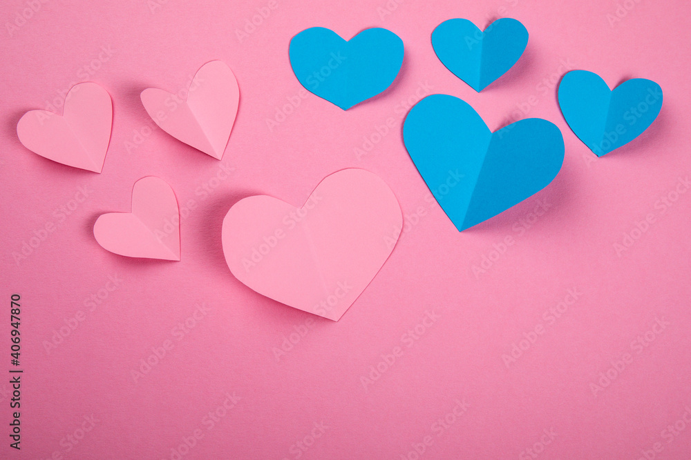 Pink and blue paper hearts on a pink background. Guys and girls, falling in love and passion concept