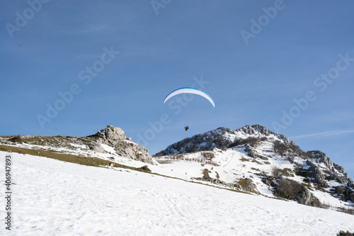 Paraglider flying over the mountains in winter
