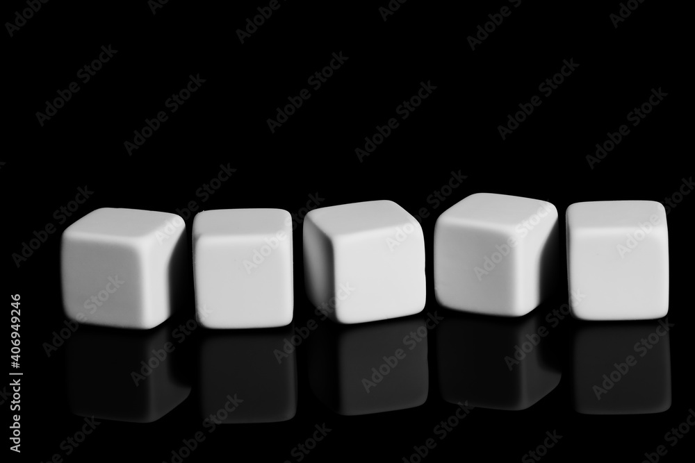 The white cubes are arranged in a chaotic order on a black surface. Close-up, isolated background, mirror image. The white cubes are arranged in a chaotic order on a black surface. Close-up, isolated background, mirror image.