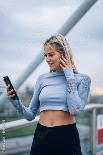 One woman listening music on wireless headphones on the bridge after working out outdoors