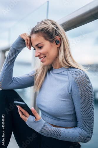 One woman listening music on wireless headphones by the river after working out
