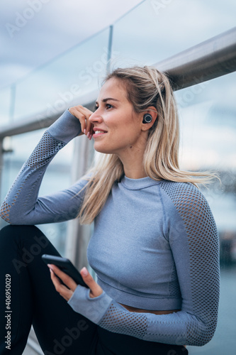 young woman listening music on her wireless earbuds after working out 