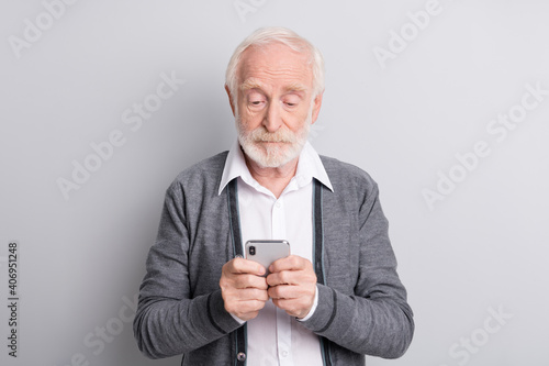 Portrait of old white hair serious man type telephone wear dark sweater isolated on grey background © deagreez