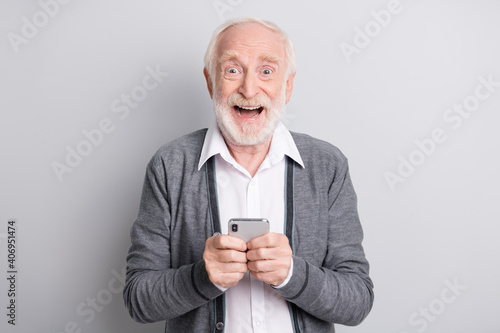 Portrait of old white hair hooray man hold telephone wear dark sweater isolated on grey background © deagreez