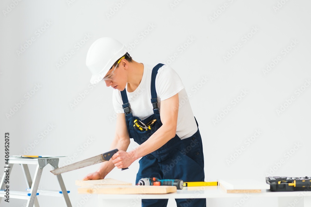 carpenter sawing white board during apartment renovating carpenter sawing white board during apartment renovating