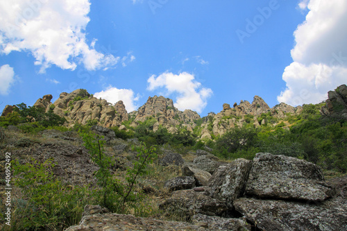 View of the cliffs on a sunny day. A warm sunny day on the Crimean peninsula. Bright blue sky with white clouds. Sunlight on the mountains tops.