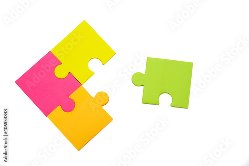 Three different colored pieces of puzzle are put together and one apart from them, isolated on a white background. Close-up, copy space, flat lay. The concept of connection, connection.