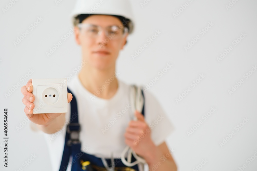 Young electrician on white background. Holds a cable and sockets. Young electrician on white background. Holds a cable and sockets.