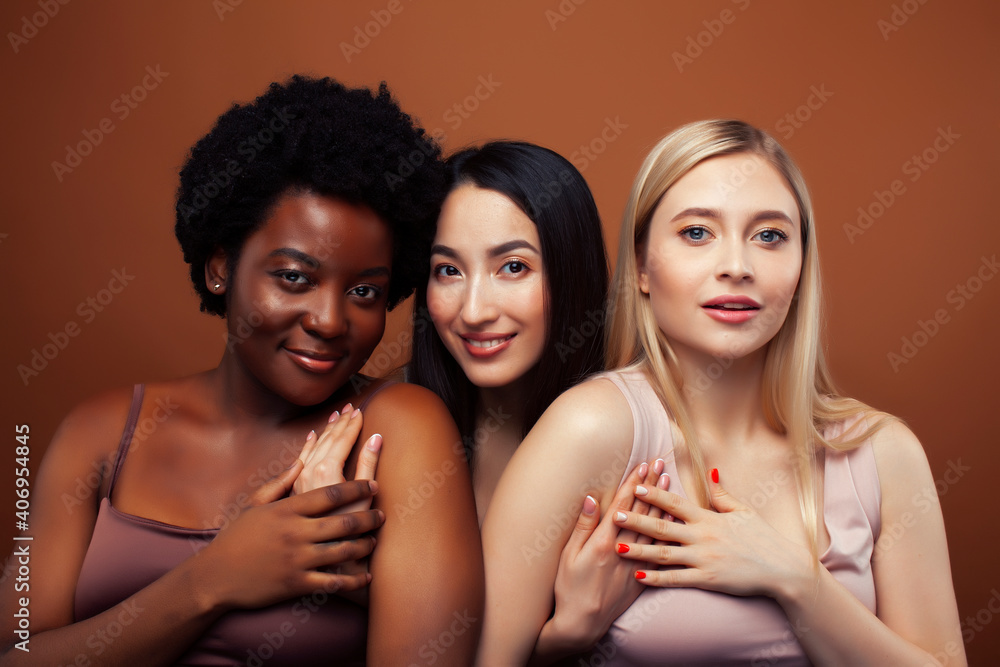 Obraz premium young pretty asian, caucasian, afro woman posing cheerful together on brown background, lifestyle diverse nationality people concept