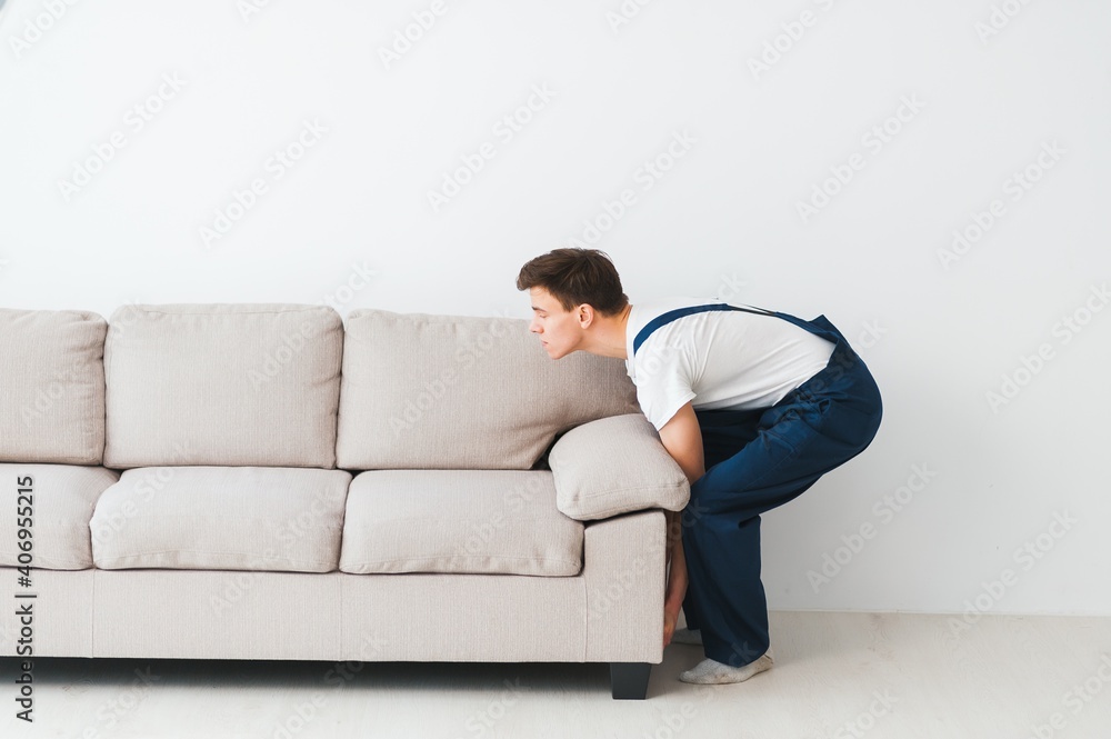 Loader moves sofa, couch. worker in overalls lifts up sofa, white background. Delivery service concept. Courier delivers furniture in case of move out, relocation. Loader moves sofa, couch. worker in overalls lifts up sofa, white background. Delivery service concept. Courier delivers furniture in case of move out, relocation.