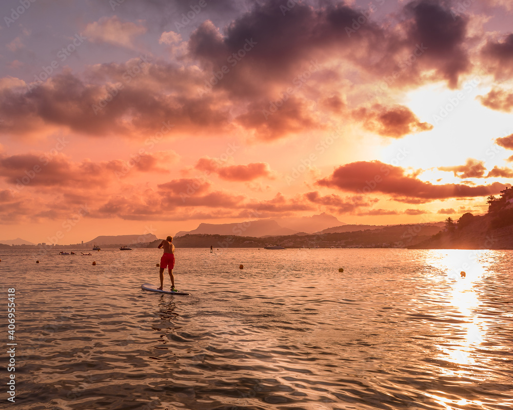 Person doing paddle surf in with a beautiful sunset on the beach
