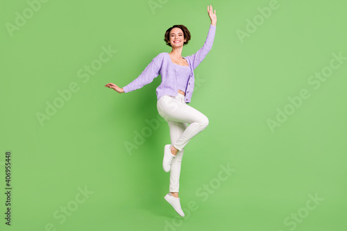 Full body portrait of cheerful carefree person jumping partying beaming smile isolated on green color background