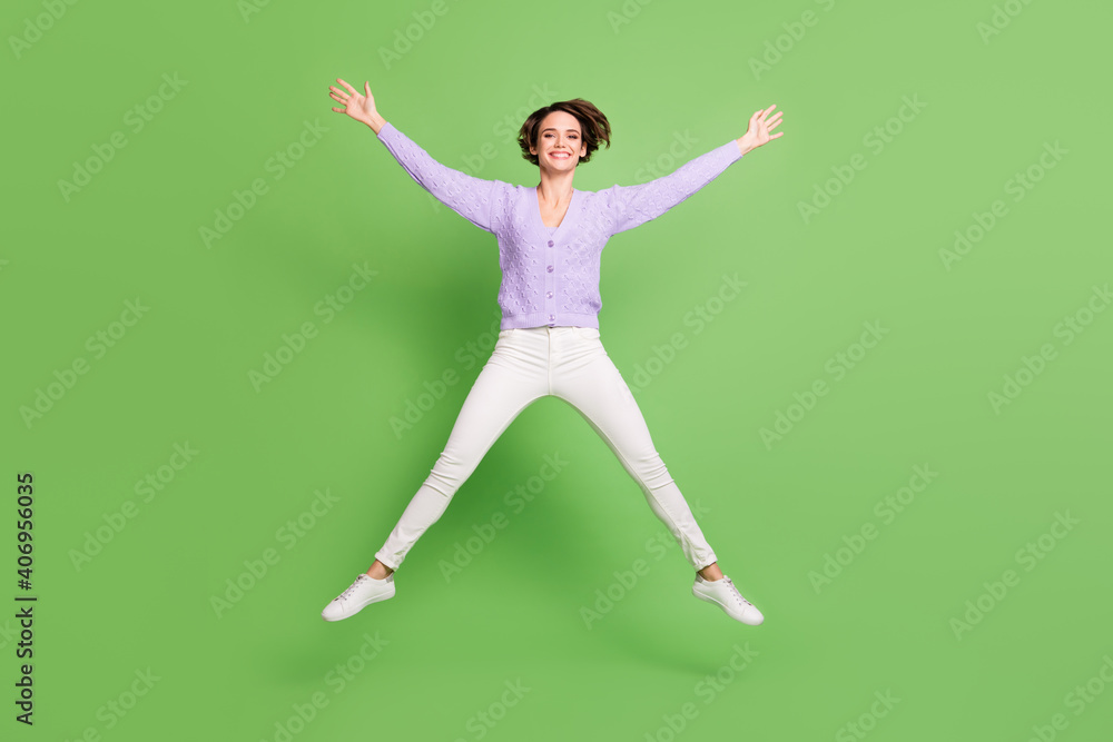 Full length portrait of cheerful lady jumping high make star figure toothy smile isolated on green color background Full length portrait of cheerful lady jumping high make star figure toothy smile isolated on green color background