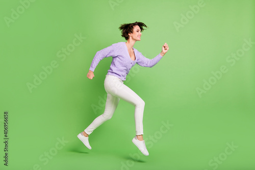 Full length profile portrait of carefree lady look empty space running toothy smile isolated on green color background