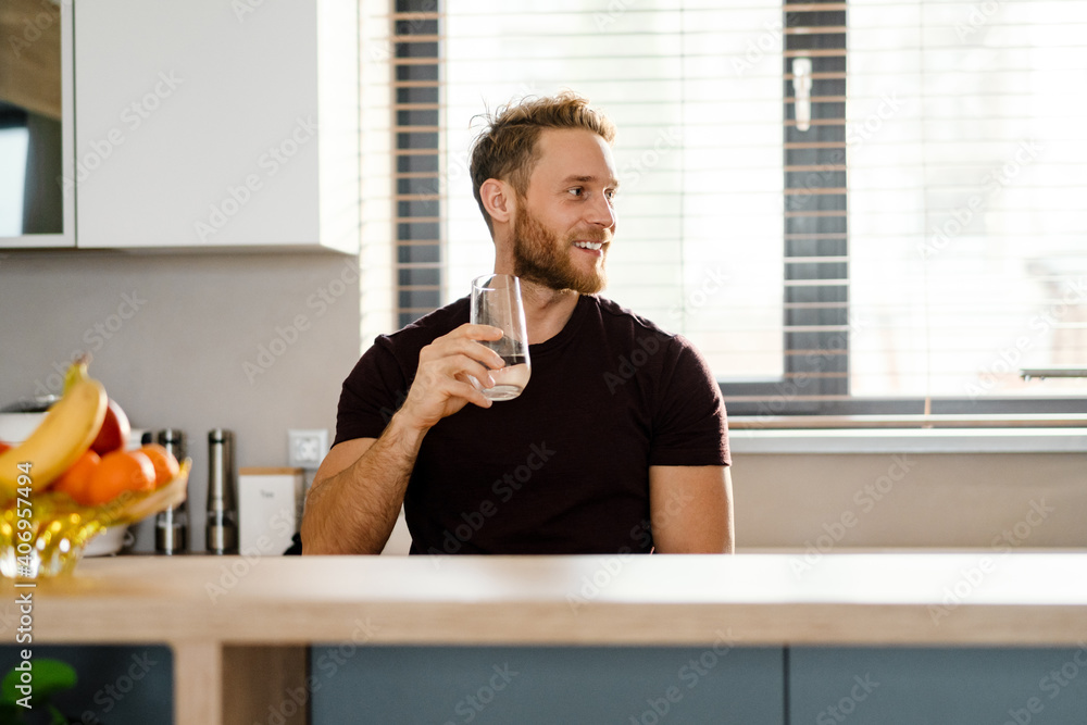 Smiling healthy man drinking water from a glass