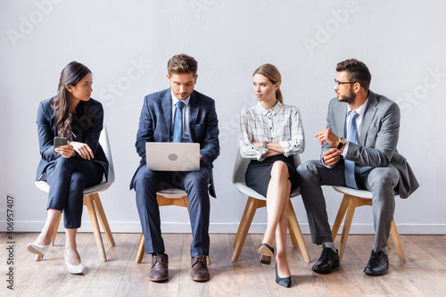 Quadro su tela Multiethnic businesspeople looking at businessman with laptop before job intervi