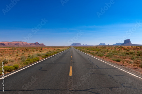 Scenic view of the US highway 163 leading to the Monument Valley with sandstone buttes on the background; Concept for travel in the USA and road trip.