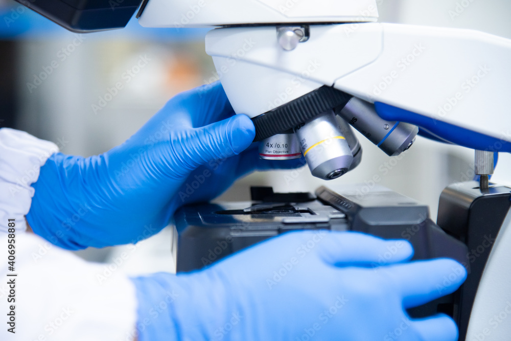 Close up hand scientist in blue glove using microscope. Close up hand scientist in blue glove using microscope.