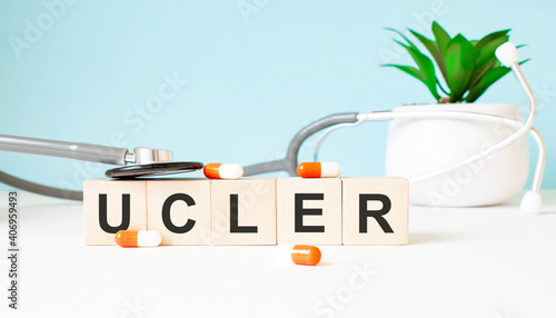 The word UCLER is written on wooden cubes near a stethoscope on a wooden background. Medical concept photo