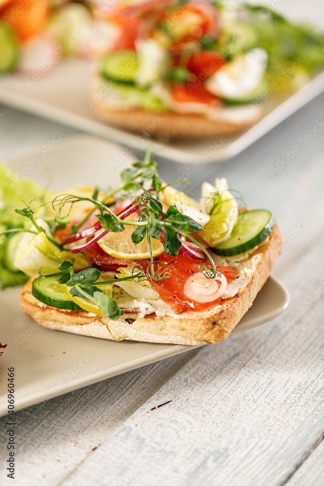 Quick and healthy food recipes. Salad with salmon, vegetables and herbs on Italian ciabatta bread. Mediterranean dish recipes. Selective focus. Vertical shot